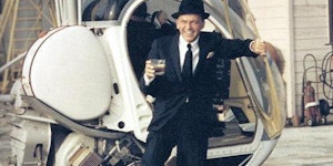 Frank Sinatra exiting a helicopter with drink in hand, 1964.